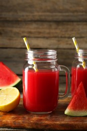 Photo of Tasty watermelon drink in mason jars and fresh fruits on wooden table, closeup