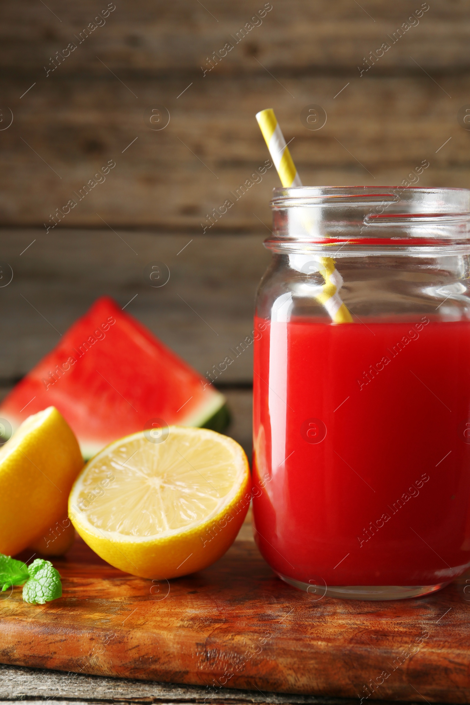 Photo of Tasty watermelon drink in mason jar and fresh fruits on wooden table, closeup