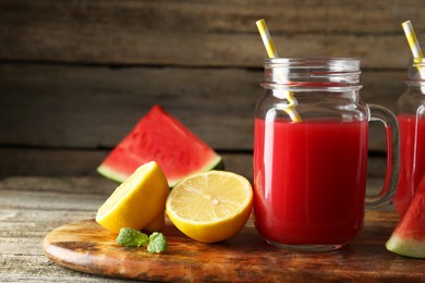 Photo of Tasty watermelon drink in mason jars and fresh fruits on wooden table, closeup