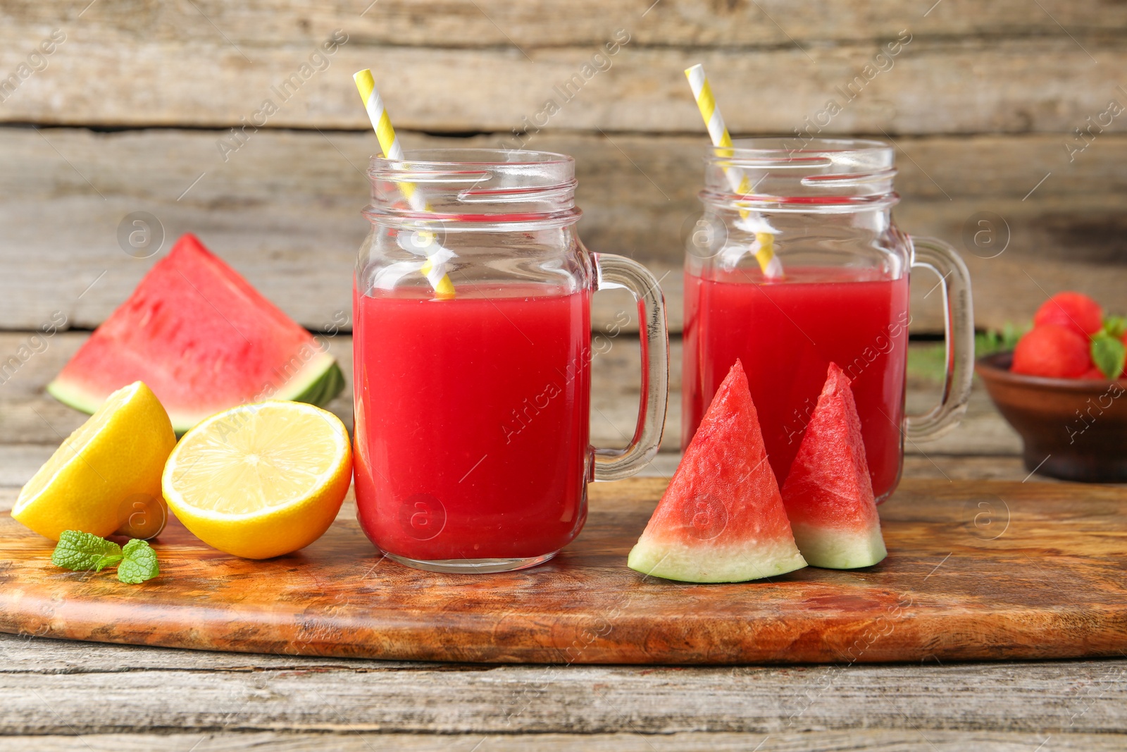 Photo of Tasty watermelon drink in mason jars and fresh fruits on wooden table