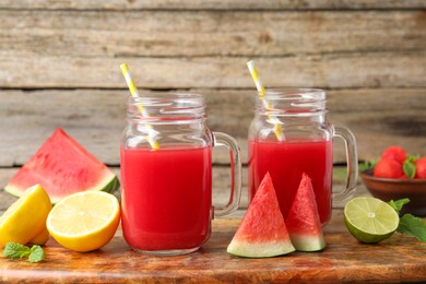 Photo of Tasty watermelon drink in mason jars and fresh fruits on wooden table