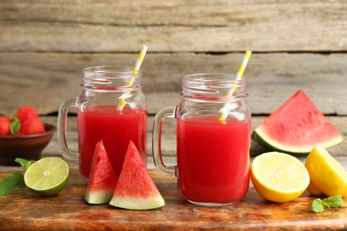 Photo of Tasty watermelon drink in mason jars and fresh fruits on wooden table