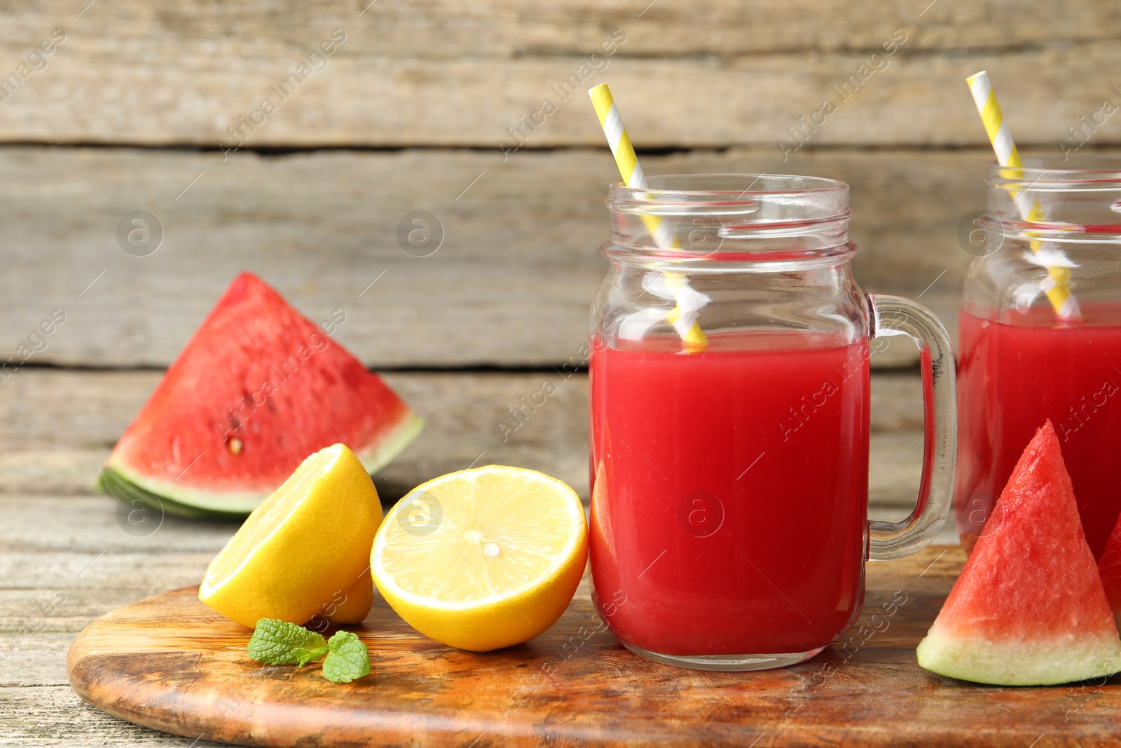 Photo of Tasty watermelon drink in mason jars and fresh fruits on wooden table, closeup