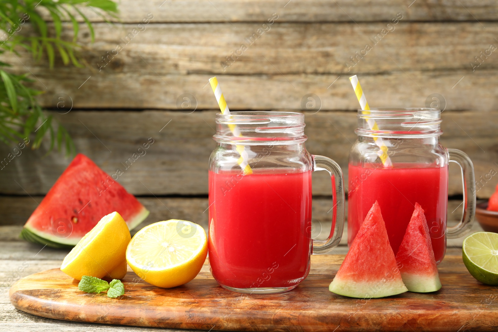 Photo of Tasty watermelon drink in mason jars and fresh fruits on wooden table