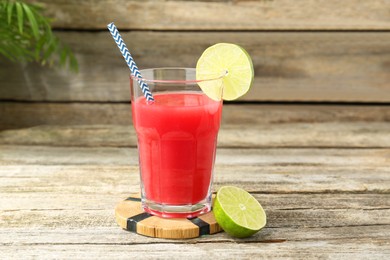 Photo of Tasty watermelon drink in glass and lime on wooden table