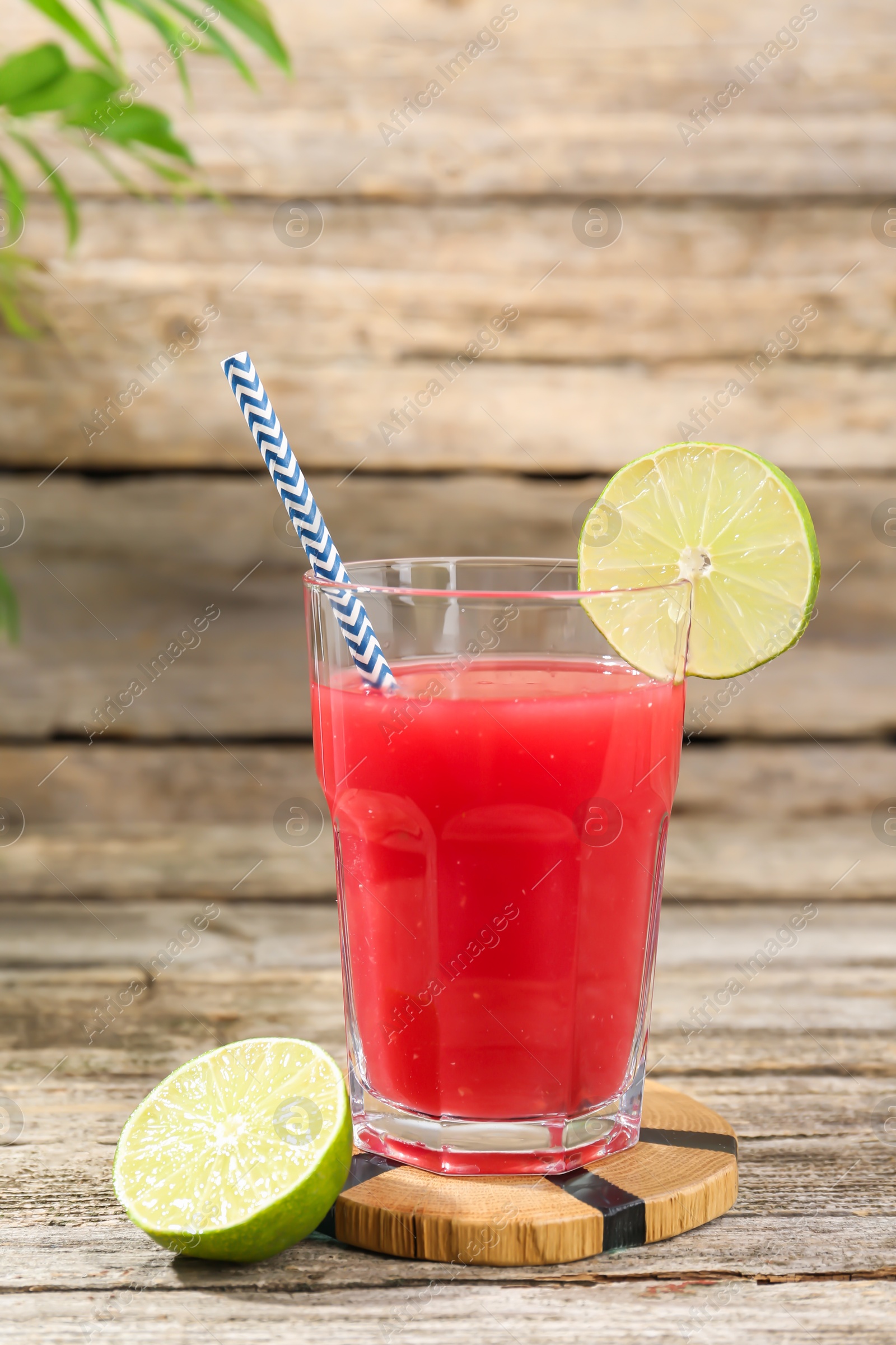 Photo of Tasty watermelon drink in glass and lime on wooden table