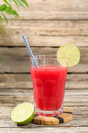 Photo of Tasty watermelon drink in glass and lime on wooden table