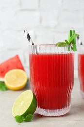 Photo of Delicious watermelon drink in glass, fresh fruits and mint on light table, closeup