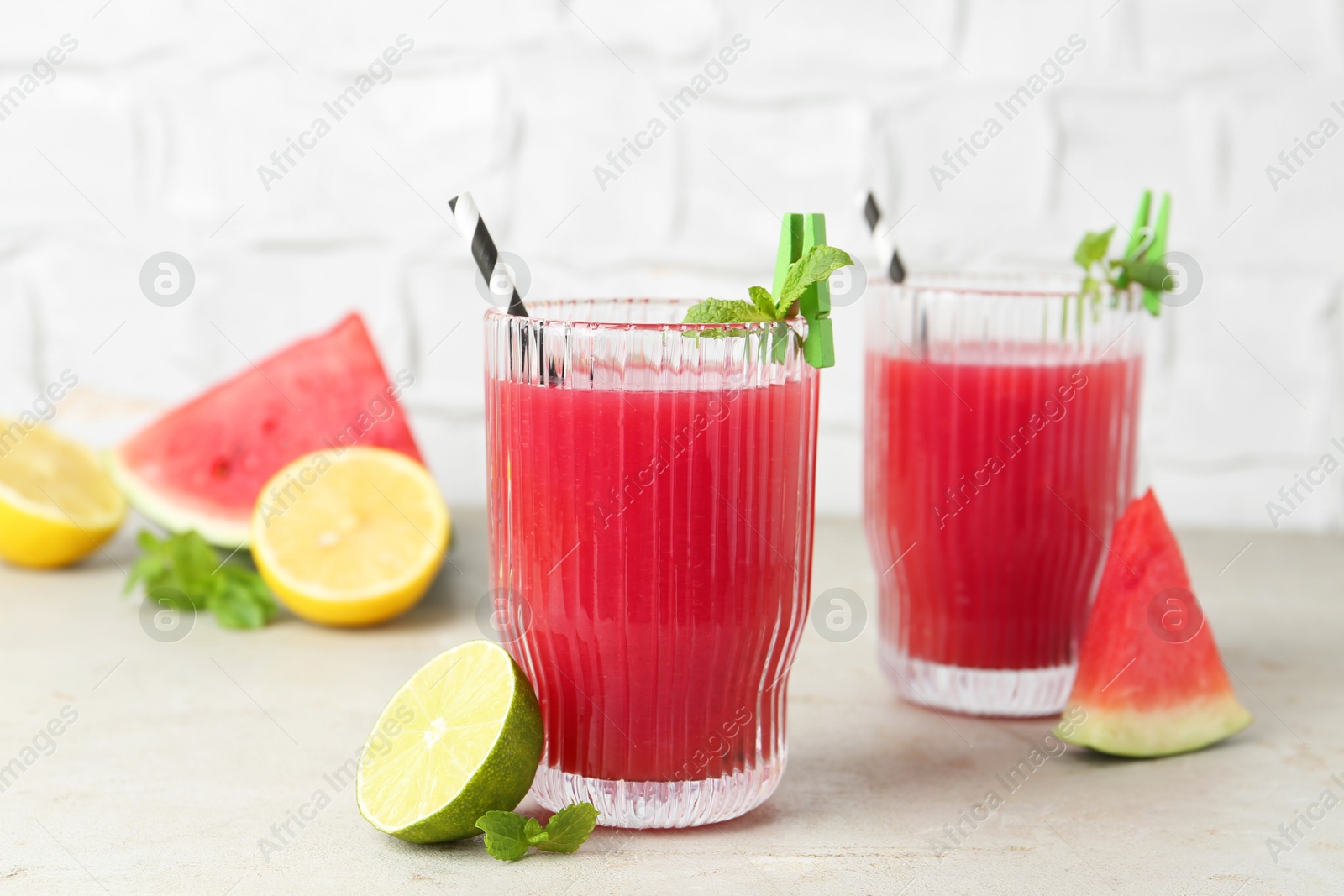 Photo of Delicious watermelon drink in glasses and fresh fruits on light table