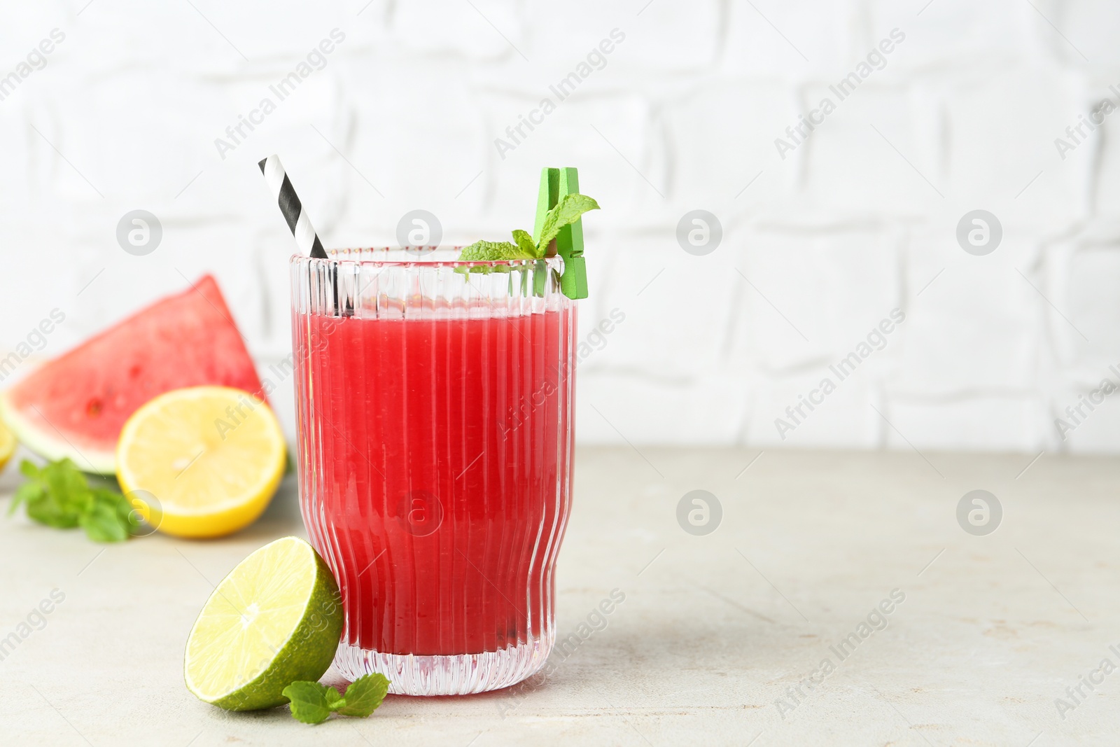 Photo of Delicious watermelon drink in glass and fresh fruits on light table. Space for text