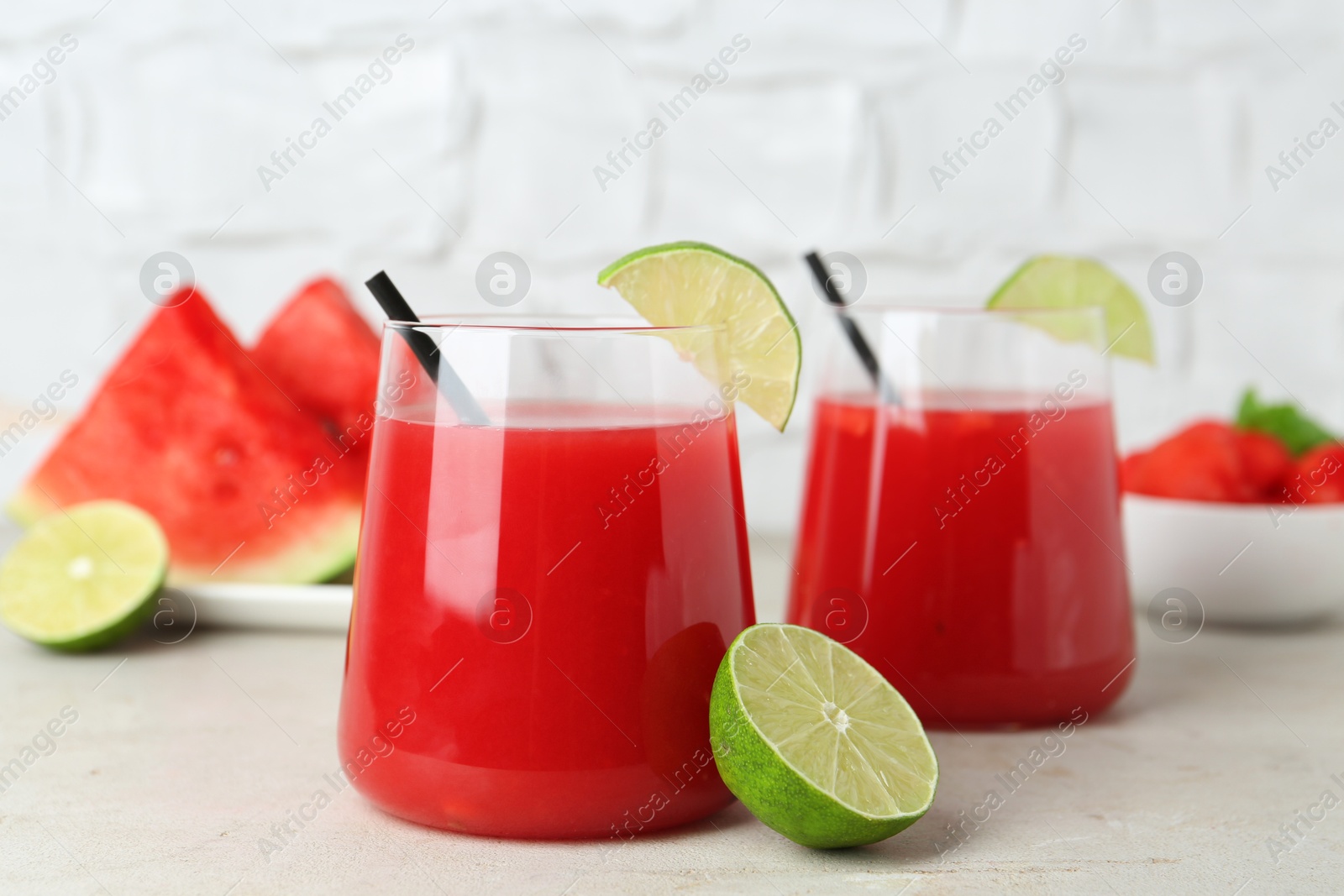 Photo of Delicious watermelon drink in glasses and fresh fruits on light table, closeup