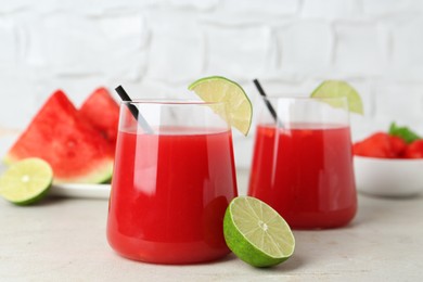 Photo of Delicious watermelon drink in glasses and fresh fruits on light table, closeup