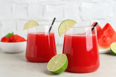 Photo of Delicious watermelon drink in glasses and fresh fruits on light table, closeup