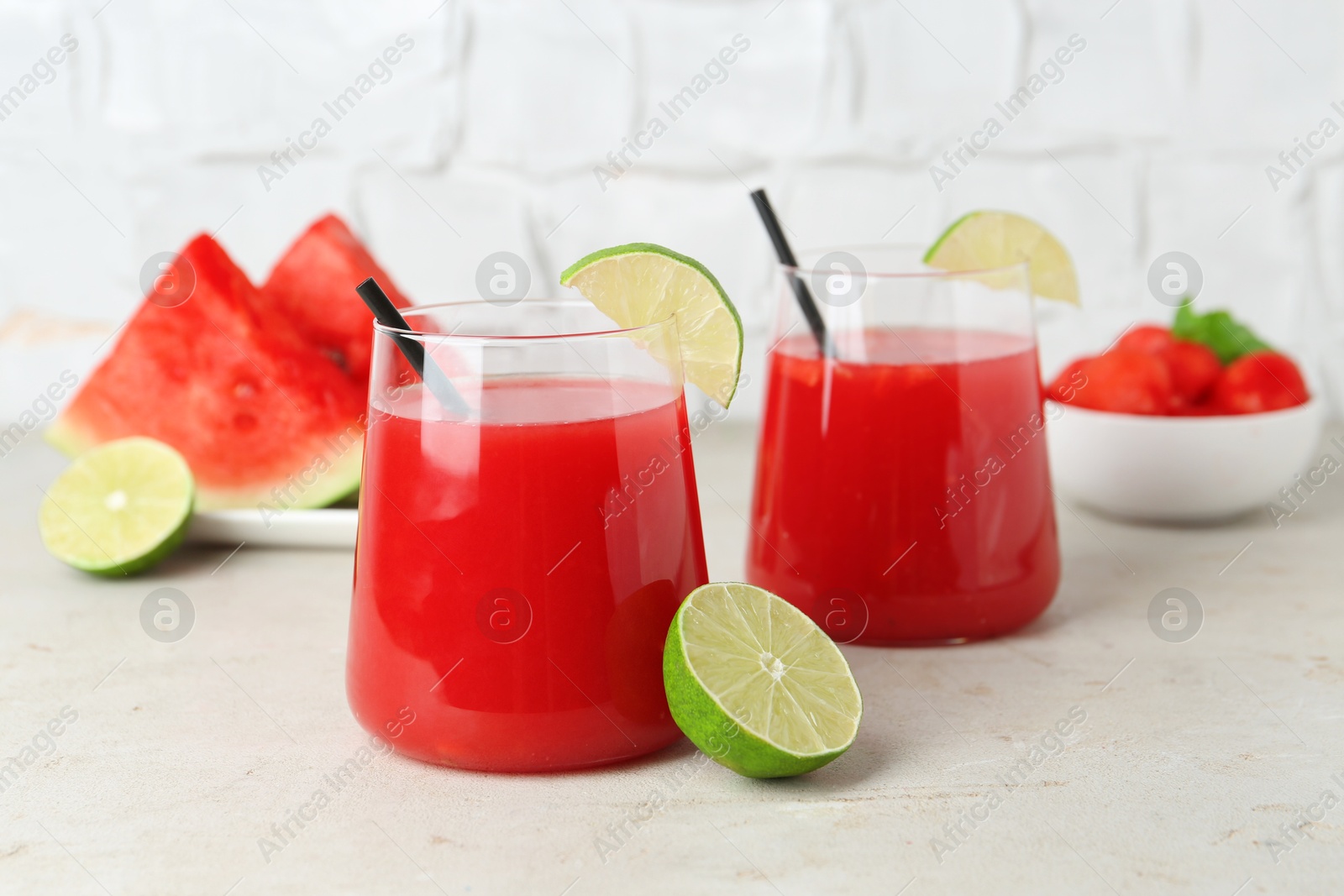 Photo of Delicious watermelon drink in glasses and fresh fruits on light table