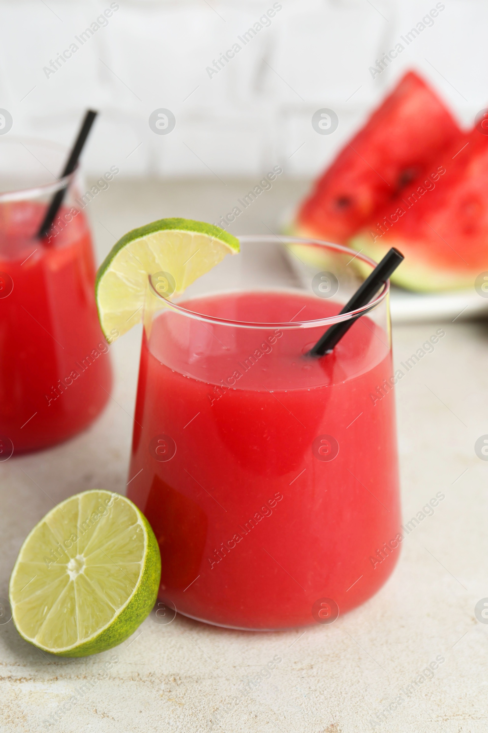 Photo of Delicious watermelon drink in glasses and fresh fruits on light table, closeup