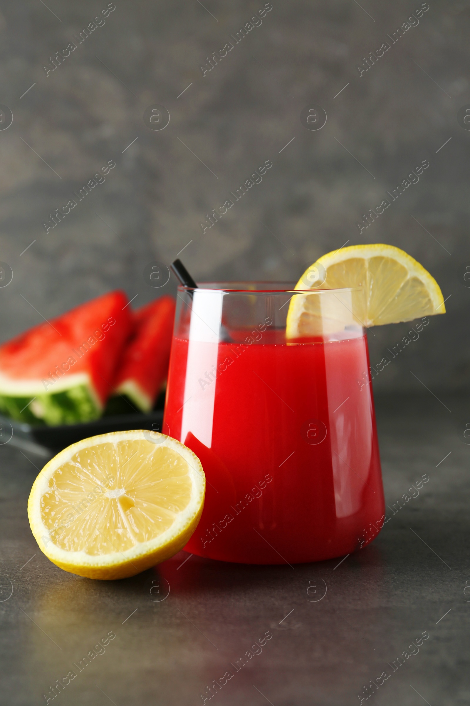 Photo of Delicious watermelon drink in glass and fresh fruits on dark grey table