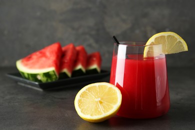 Photo of Delicious watermelon drink in glass and fresh fruits on dark grey table