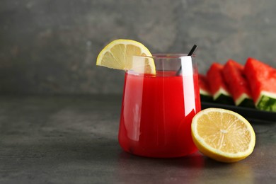 Photo of Delicious watermelon drink in glass and fresh fruits on dark grey table. Space for text