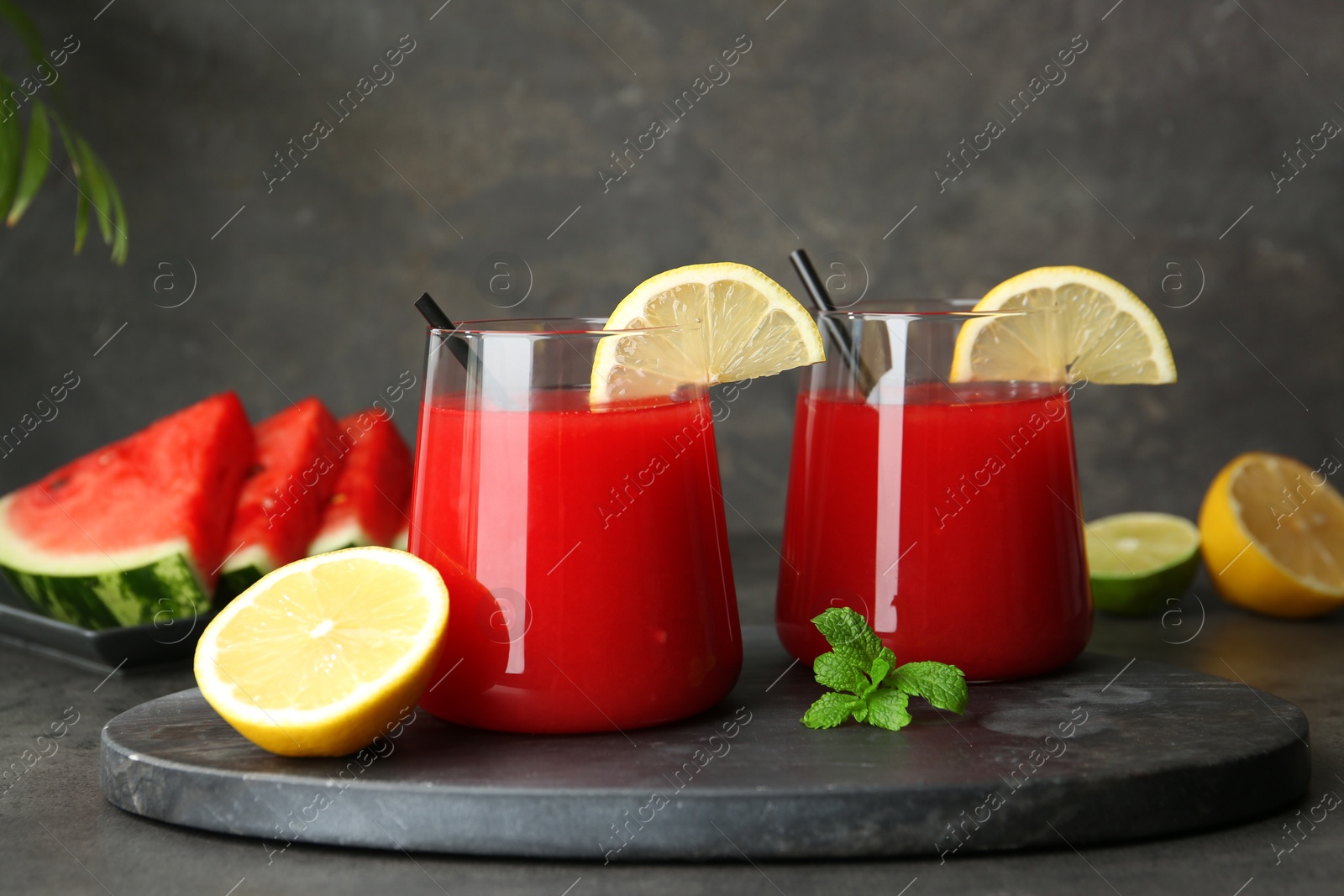 Photo of Delicious watermelon drink in glasses, fresh fruits and mint on grey table