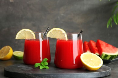 Photo of Delicious watermelon drink in glasses, fresh fruits and mint on grey table