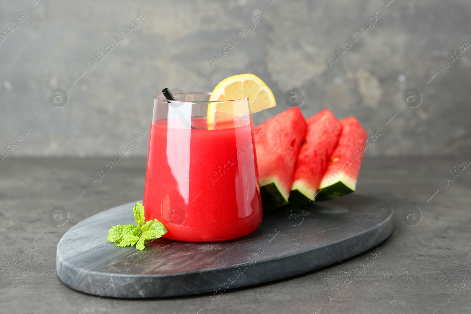 Photo of Tasty watermelon drink in glass, fresh fruits and mint on grey table