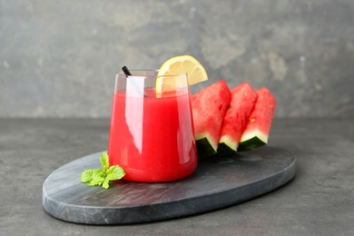 Photo of Tasty watermelon drink in glass, fresh fruits and mint on grey table