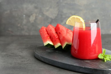 Photo of Tasty watermelon drink in glass, fresh fruits and mint on grey table. Space for text