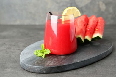 Photo of Tasty watermelon drink in glass, fresh fruits and mint on grey table