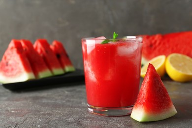 Photo of Tasty watermelon drink in glass, fresh fruits and mint on grey table, closeup