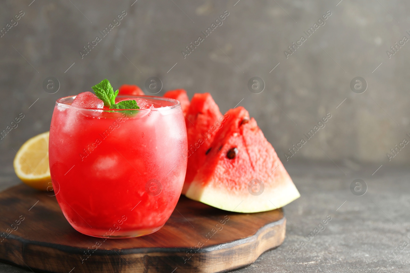 Photo of Tasty watermelon drink in glass, fresh fruits and mint on grey table, closeup