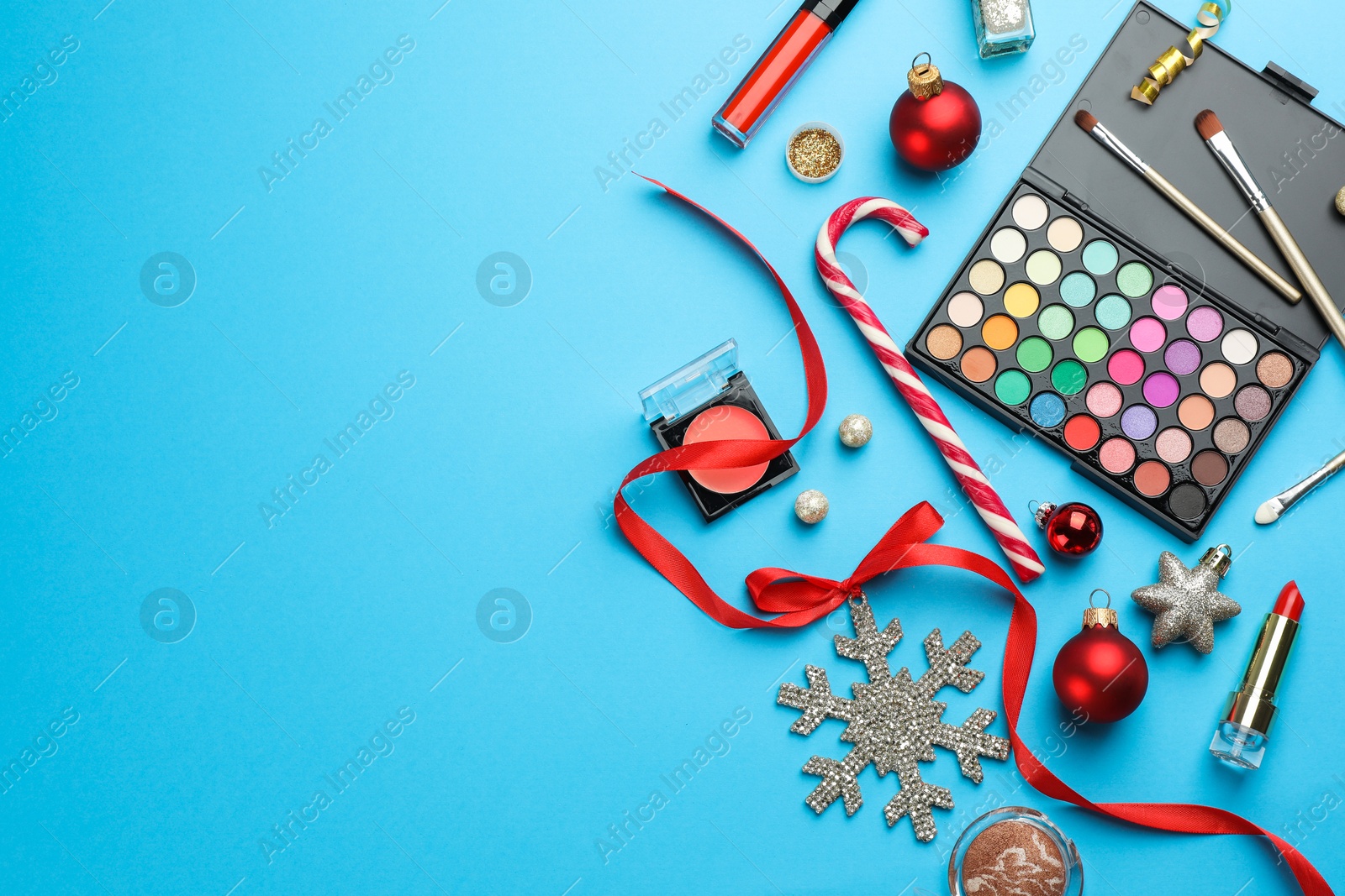 Photo of Different decorative cosmetic products and Christmas decor on light blue background, flat lay. Space for text