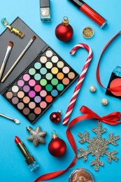 Photo of Different decorative cosmetic products and Christmas decor on light blue background, flat lay