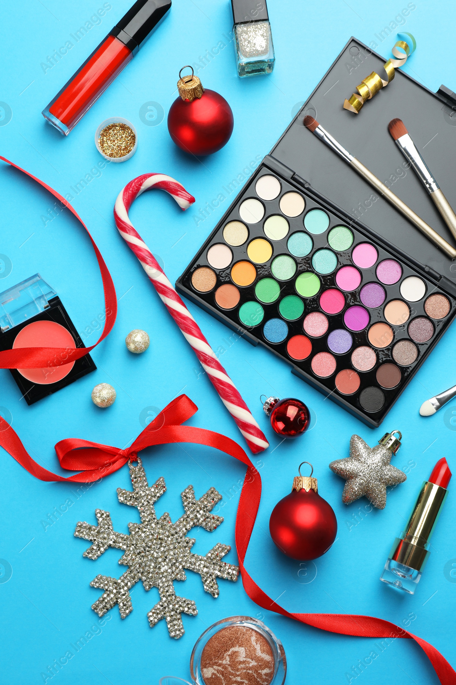 Photo of Different decorative cosmetic products and Christmas decor on light blue background, flat lay