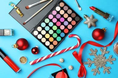 Photo of Different decorative cosmetic products and Christmas decor on light blue background, flat lay