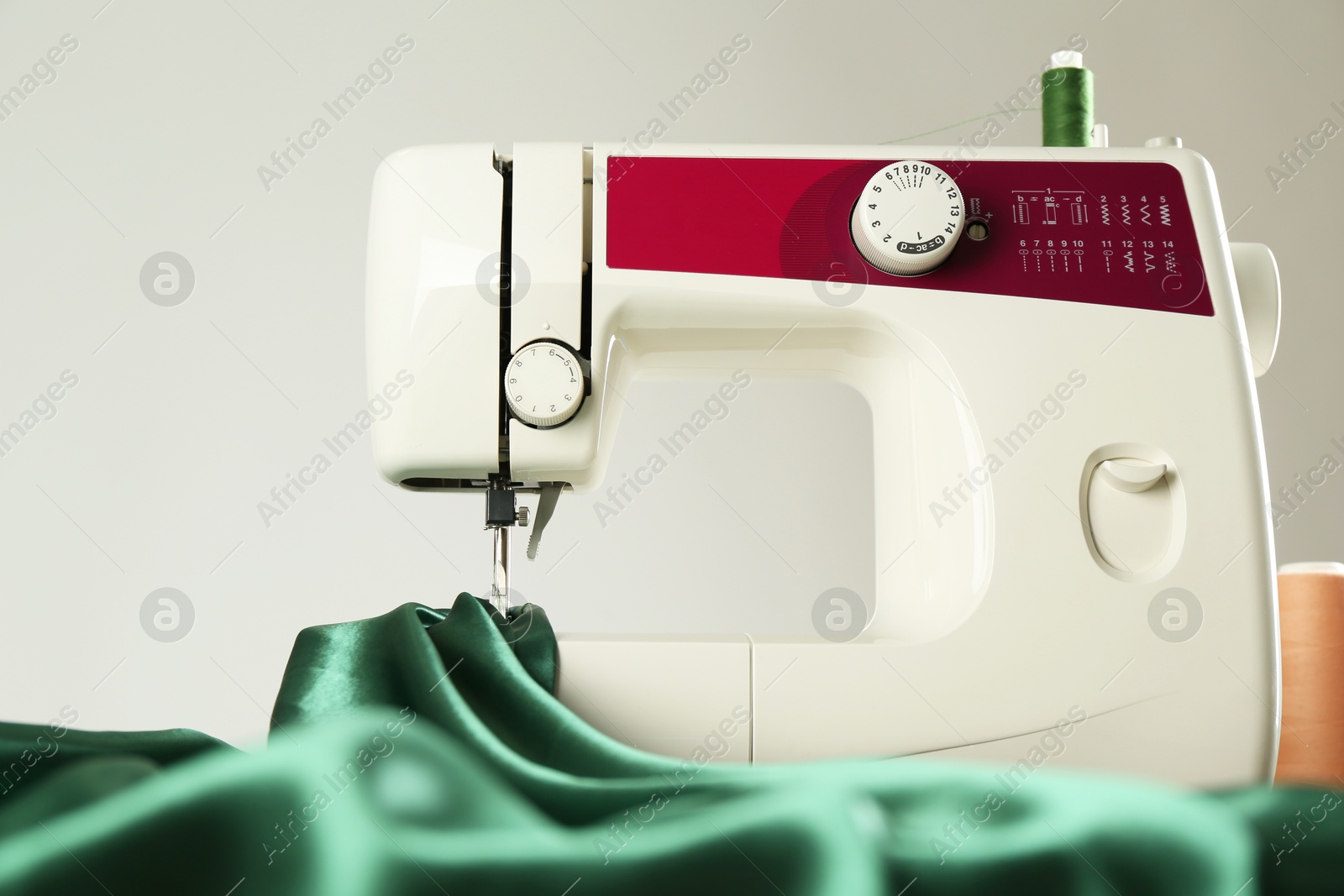 Photo of Sewing machine with green fabric on light background