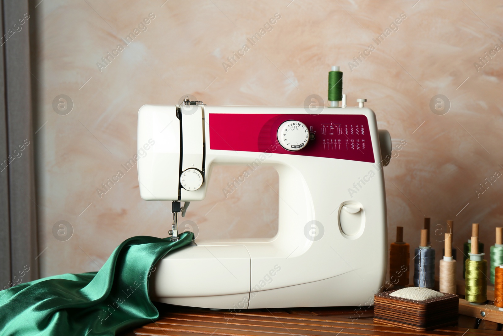 Photo of Sewing machine, green fabric and craft accessories on wooden table indoors