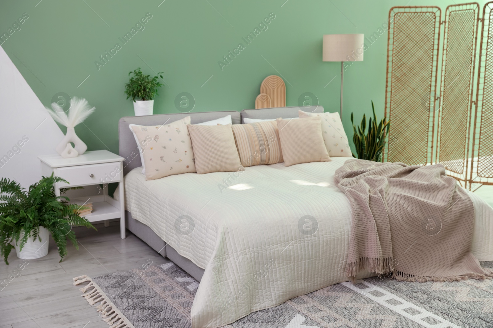 Photo of Stylish bedroom interior with large bed, houseplants and decorative elements