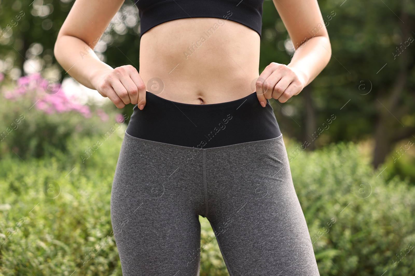 Photo of Woman wearing stylish sports leggings outdoors, closeup