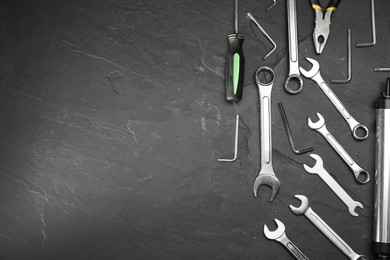 Photo of Parts of bicycle and tools on black table, flat lay. Space for text