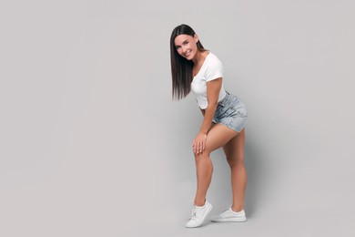 Photo of Beautiful woman wearing stylish denim shorts on gray background