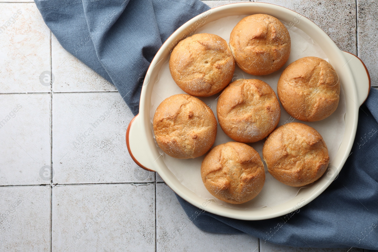 Photo of Baking dish with homemade tasty buns on textured tiled table, top view. Space for text