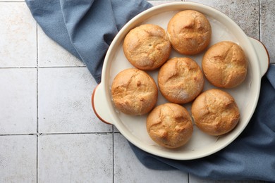 Photo of Baking dish with homemade tasty buns on textured tiled table, top view. Space for text