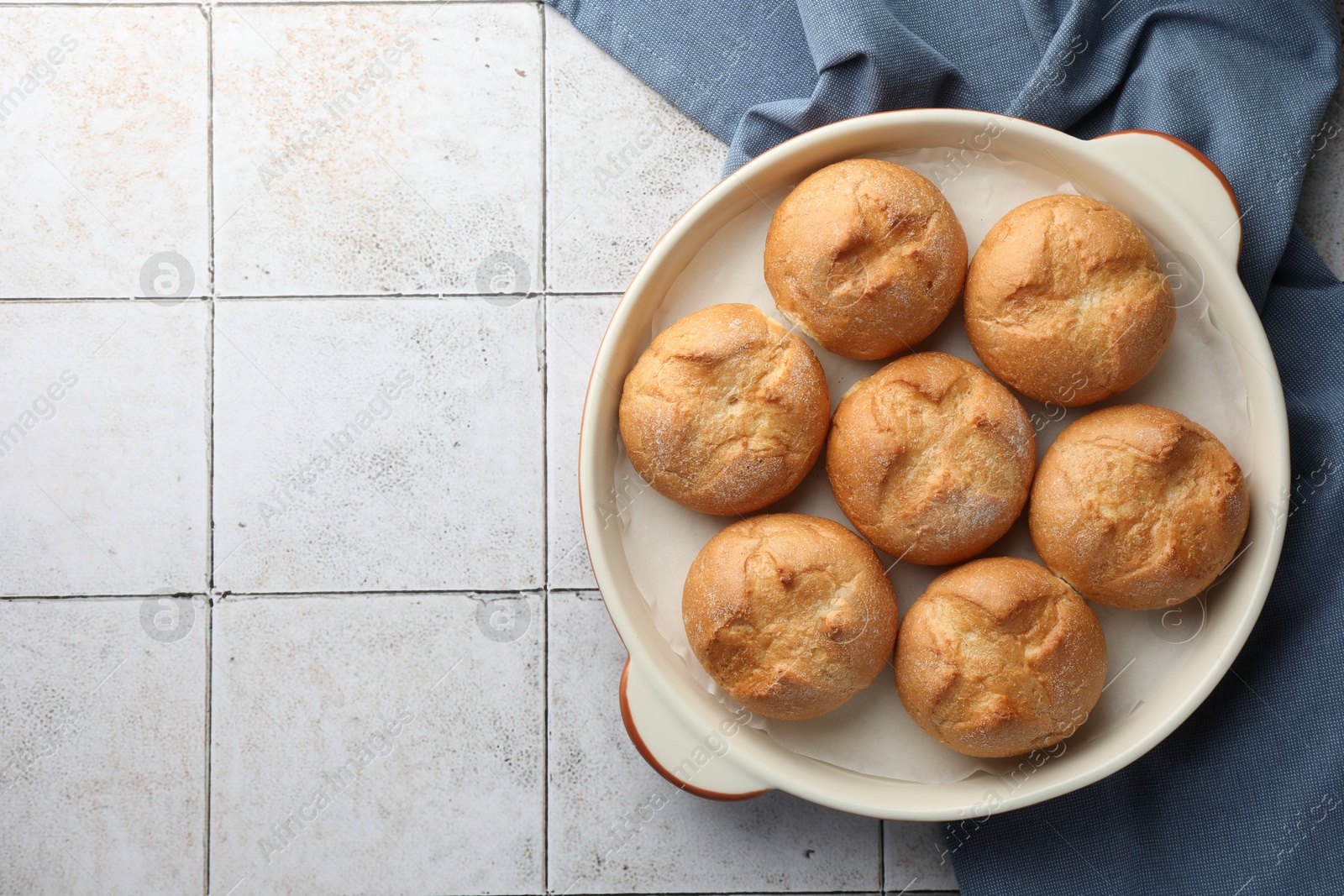 Photo of Baking dish with homemade tasty buns on textured tiled table, top view. Space for text