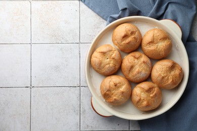 Baking dish with homemade tasty buns on textured tiled table, top view. Space for text