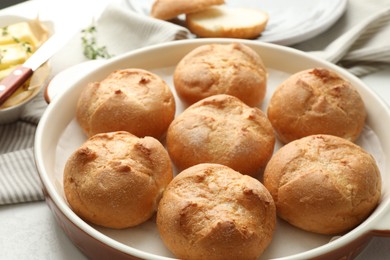 Photo of Baking dish with homemade tasty buns on light table, closeup