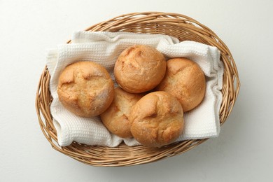 Photo of Wicker basket with homemade tasty buns on white table, top view