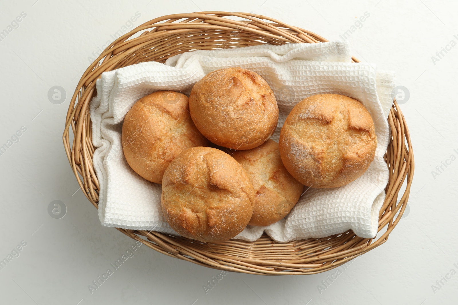 Photo of Wicker basket with homemade tasty buns on white table, top view