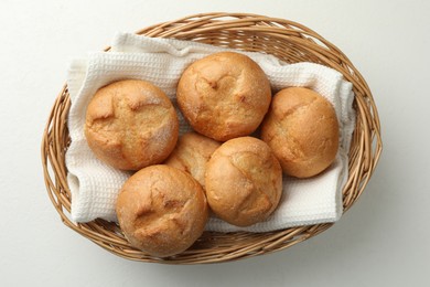 Wicker basket with homemade tasty buns on white table, top view