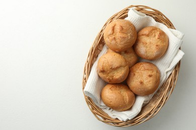 Wicker basket with homemade tasty buns on white table, top view. Space for text