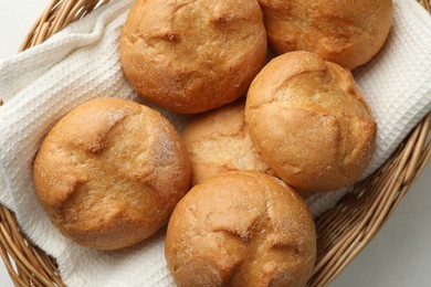 Wicker basket with homemade tasty buns on white table, top view